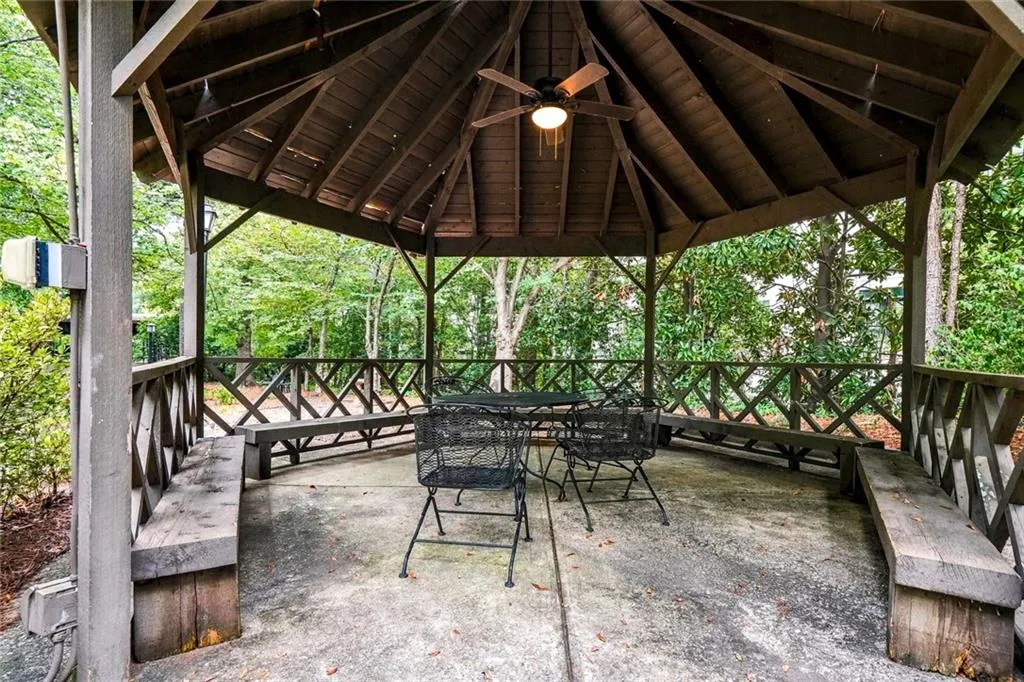 Wood-finish gazebo featuring a ceiling fan, built-in wooden benches, and decorative lattice railing
