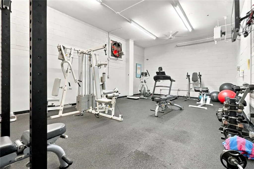 Fitness area with block walls, rubber flooring, and multiple fluorescent light fixtures