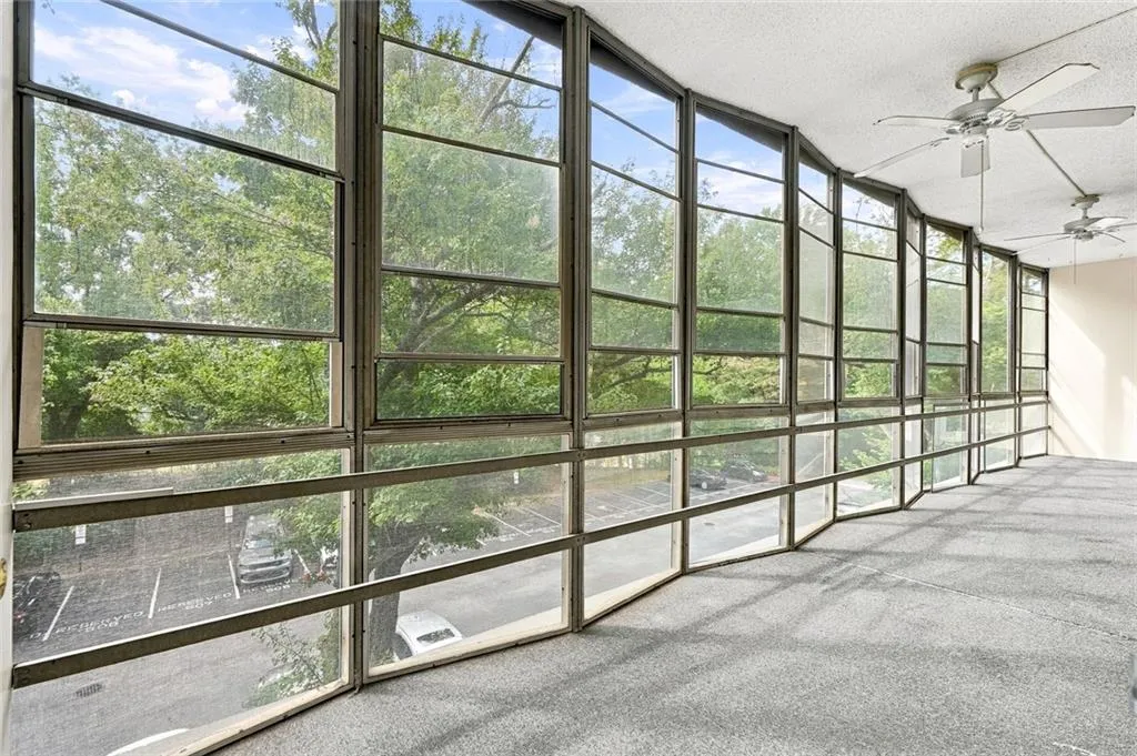 Expansive wall of windows with dark frames, textured ceiling, and two ceiling fans