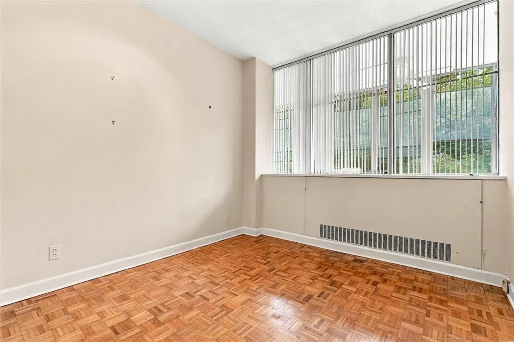 Parquet wood flooring and expansive window with vertical blinds