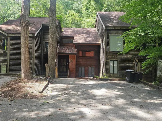 Wood-sided exterior featuring multiple gables, an asphalt driveway, mature trees, and a covered entry