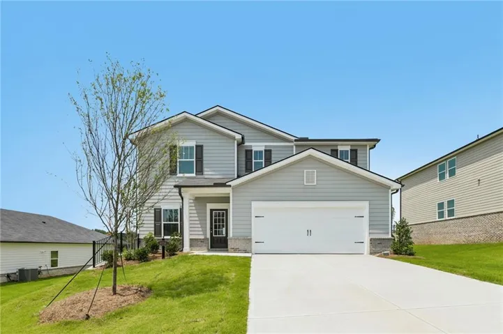 Two-story residence featuring light gray siding with dark shutters, a two-car garage, and a concrete driveway