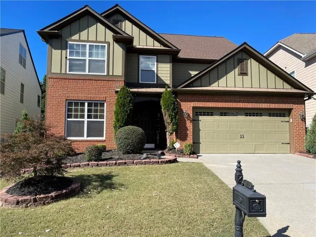 Traditional-style residence featuring a brick and siding exterior, an attached two-car garage, and established front landscaping