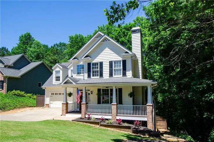 White siding exterior with a prominent front porch, a two-car garage, and a brick-clad chimney