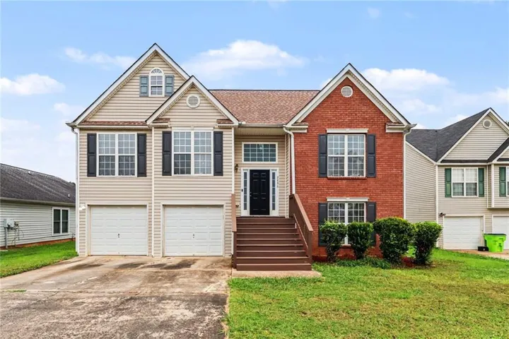 Two-story residence featuring a combination of brick and siding, a covered entry with steps, and a two-car garage