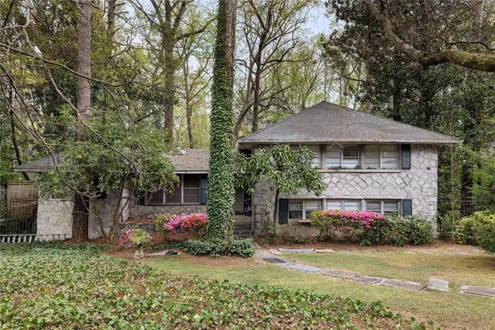 View of front facade with roof with shingles and stone siding