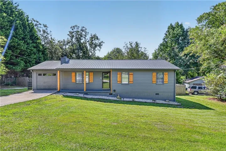 Ranch-style exterior with gray siding, a metal roof, and a single-car garage