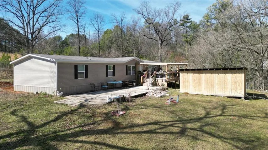 Rear view of house with a lawn, a storage unit, and a patio area