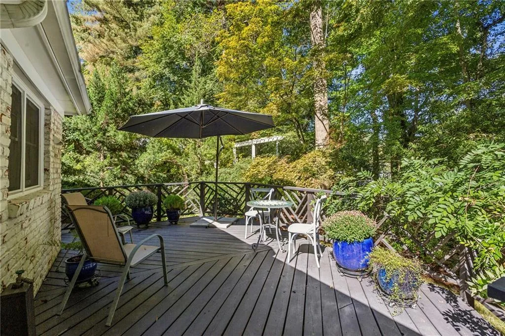 Wooden deck with view of wooded area and outdoor dining space