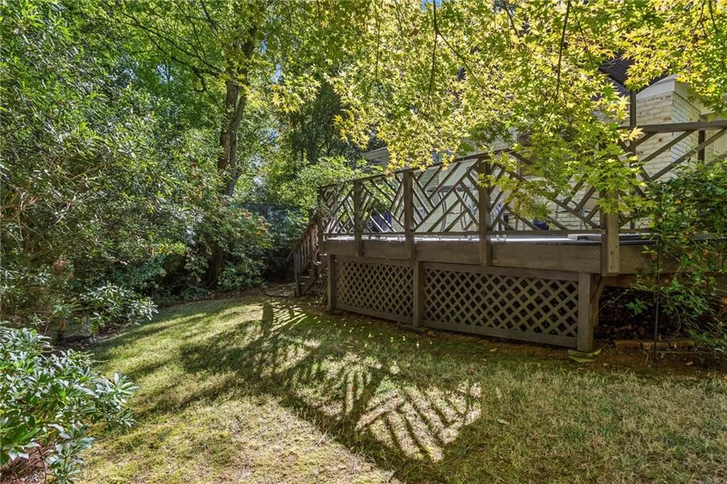 View of grassy yard with stairs and a deck