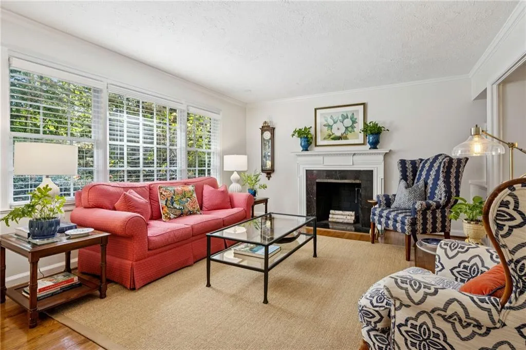Living room with a premium fireplace, wood finished floors, a textured ceiling, and ornamental molding