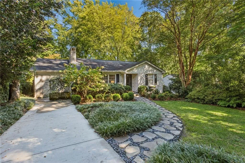 Single story home featuring a front lawn, a chimney, brick siding, and view of scattered trees