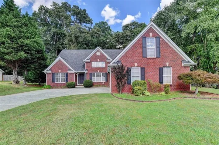 Traditional home featuring brick siding, a front lawn, and concrete driveway