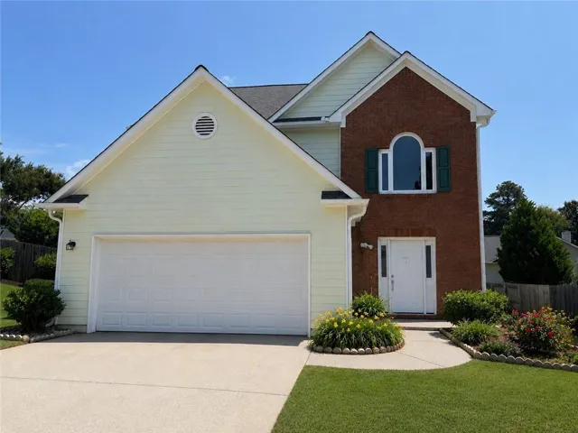 Two-story residence featuring a brick facade with light-colored siding, a two-car garage, and a concrete driveway