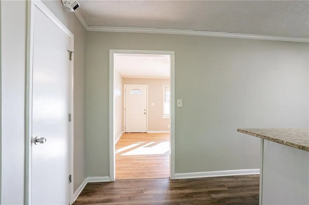 Hallway with a textured ceiling, baseboards, and ornamental molding