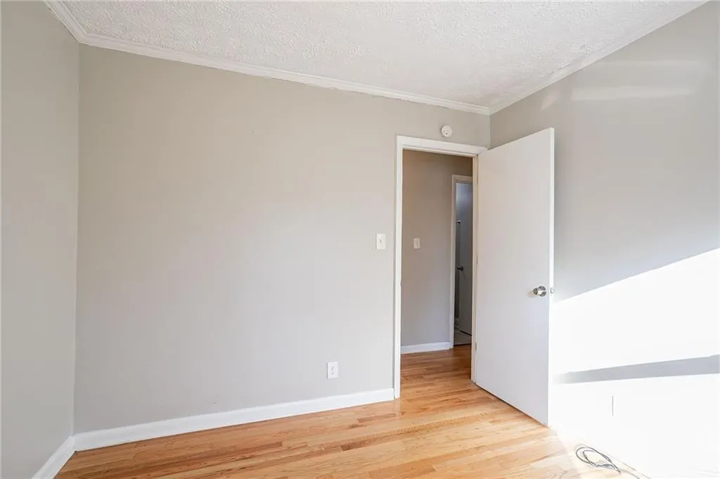 Spare room featuring a textured ceiling, crown molding, and baseboards