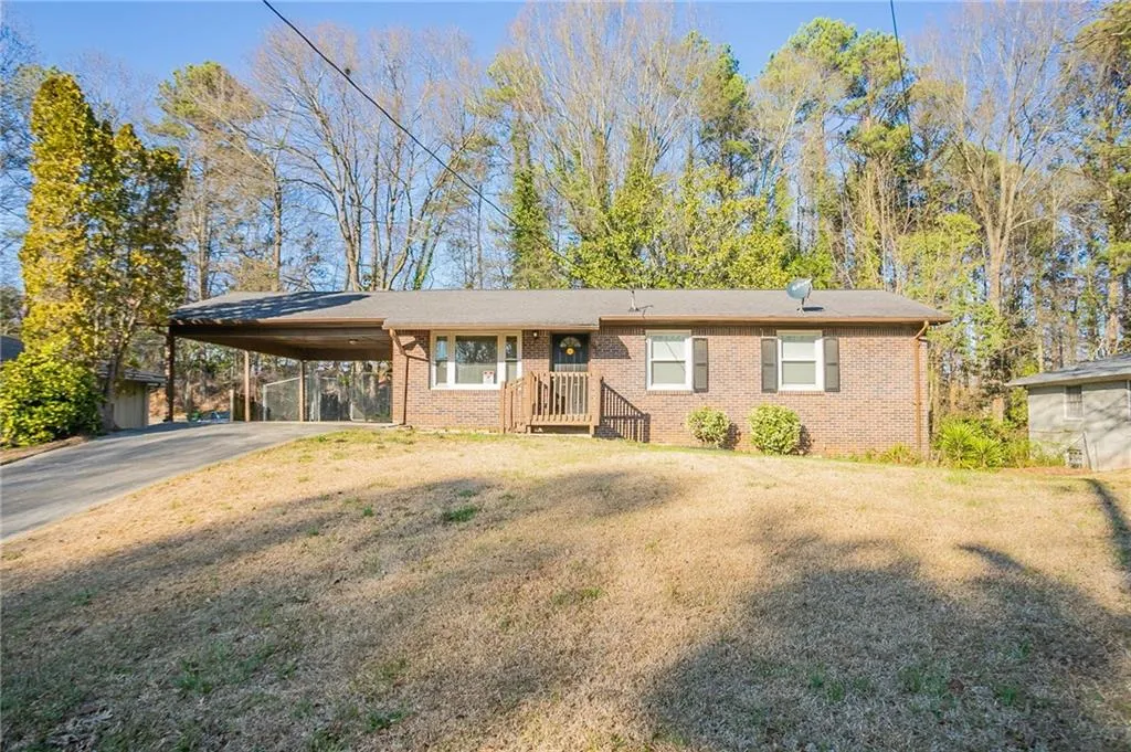 Ranch-style house with brick siding, a front lawn, an attached carport, and driveway