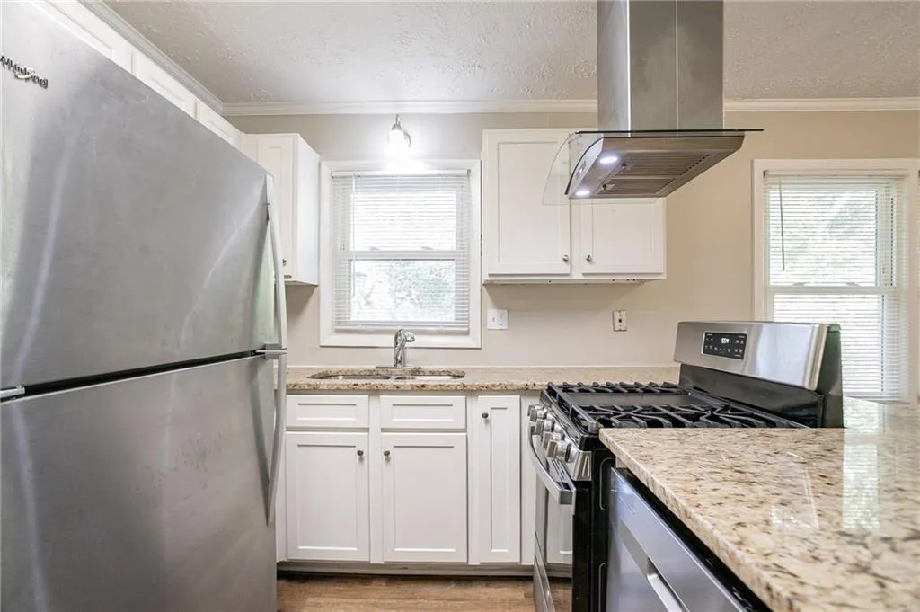 Kitchen featuring a textured ceiling, crown molding, island range hood, and stainless steel appliances