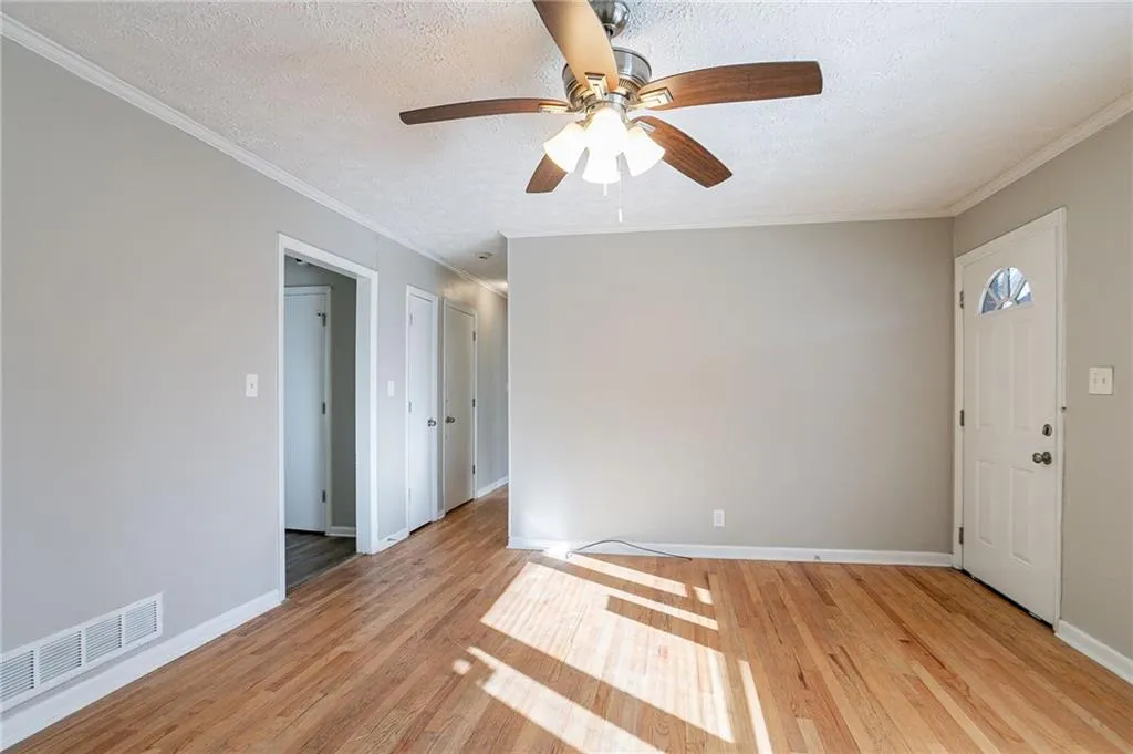 Spare room with crown molding, visible vents, light, and a textured ceiling