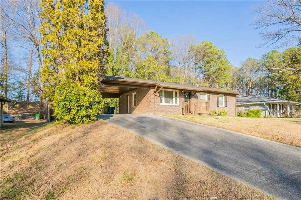 Single story home with brick siding, a front yard, a carport, and driveway