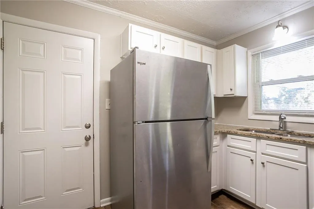 Kitchen featuring a sink, white cabinets, crown molding, and freestanding refrigerator