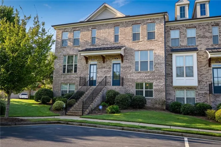 Brick exterior construction with multiple windows, prominent dormer windows, a covered entry, and a multi-level staircase with metal railings
