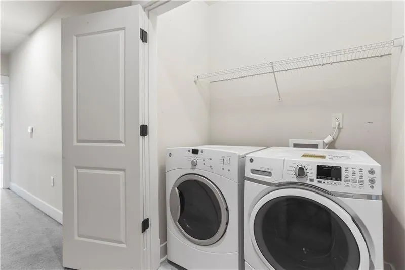 Laundry room featuring separate washer and dryer, light carpet, and baseboards