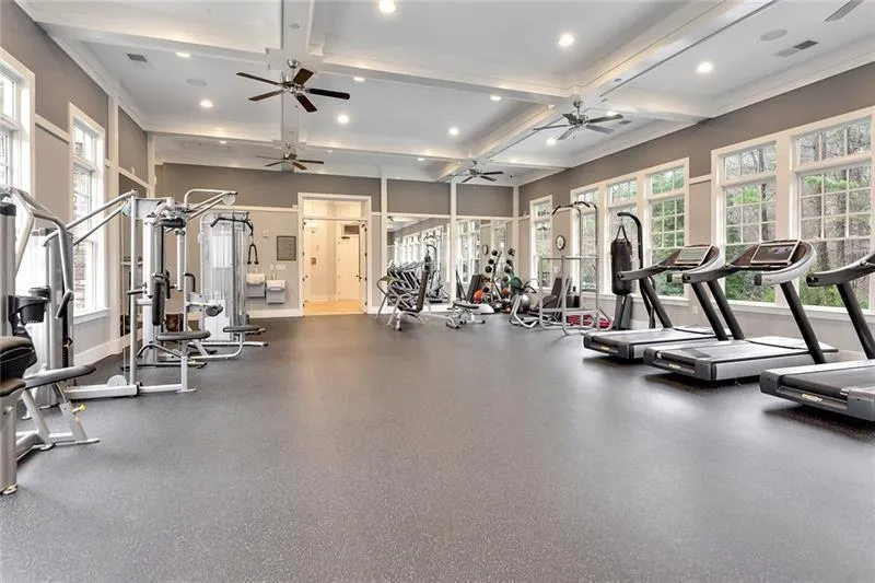 Workout area featuring coffered ceiling, a ceiling fan, recessed lighting, beamed ceiling, and baseboards