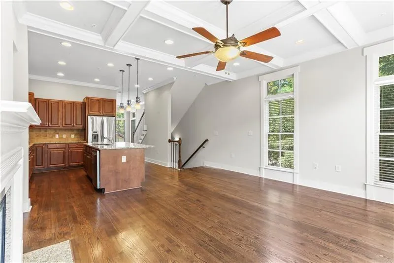 Kitchen with stainless steel appliances, coffered ceiling, plenty of natural light, a center island with sink, and dark wood-type flooring