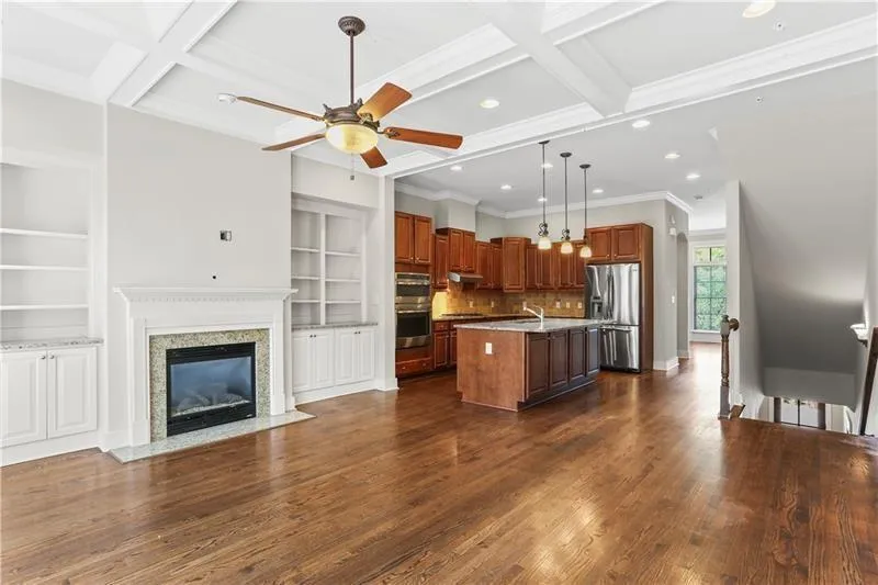 Kitchen featuring appliances with stainless steel finishes, open floor plan, coffered ceiling, an island with sink, and recessed lighting