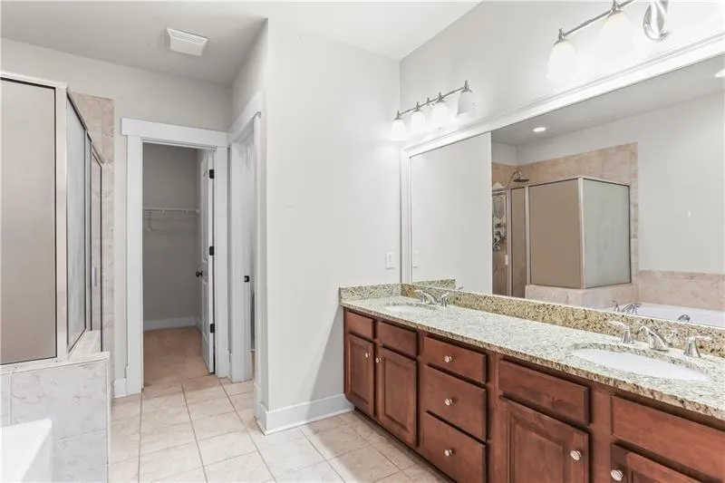 Full bath featuring tile patterned floors, a stall shower, a bath, and double vanity