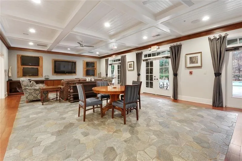 Dining room featuring light stone finish flooring, plenty of natural light, ceiling fan, coffered ceiling, and beamed ceiling