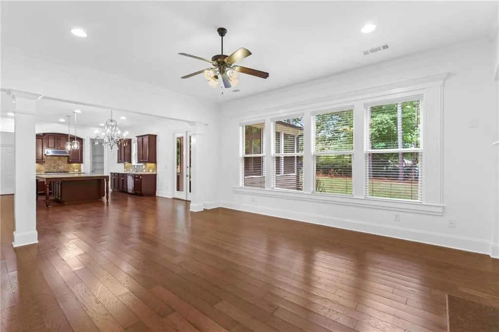 Living room with ornamental molding, ceiling fan with notable chandelier, and dark hardwood / wood-style flooring
