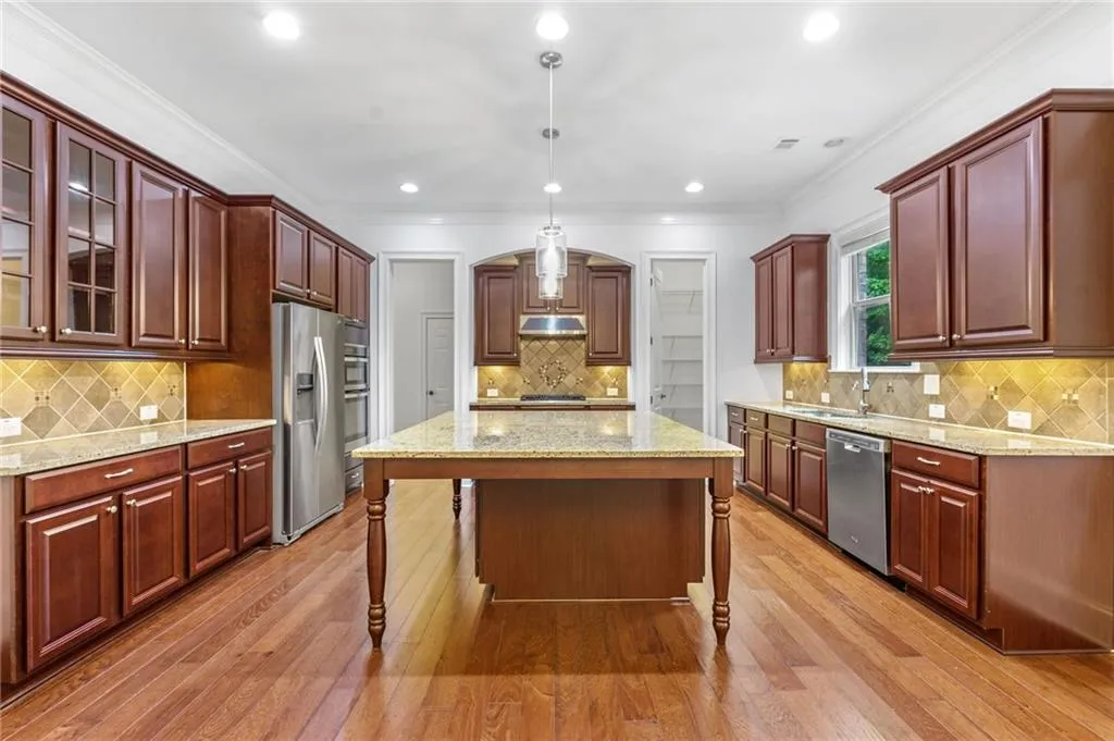 Kitchen featuring appliances with stainless steel finishes, hanging light fixtures, light hardwood / wood-style floors, and a center island
