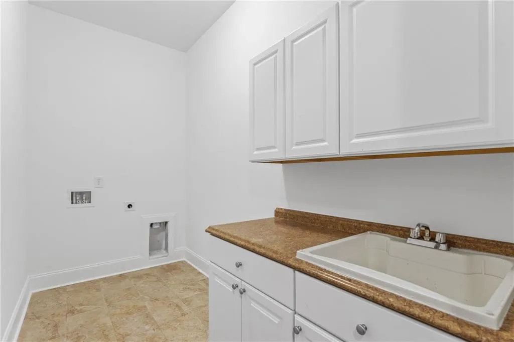 Washroom featuring cabinets, electric dryer hookup, washer hookup, and sink