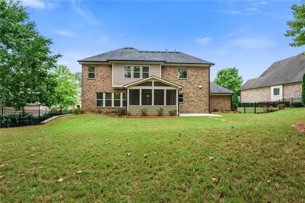 Rear view of house featuring a sunroom and a lawn