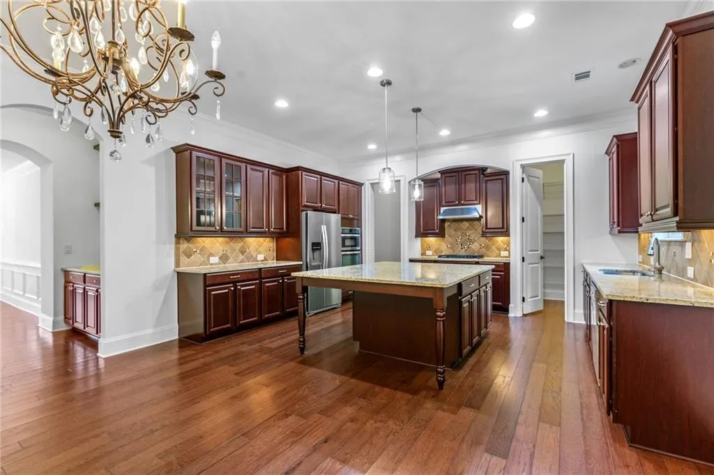 Kitchen with a center island, sink, decorative light fixtures, dark hardwood / wood-style flooring, and ornamental molding