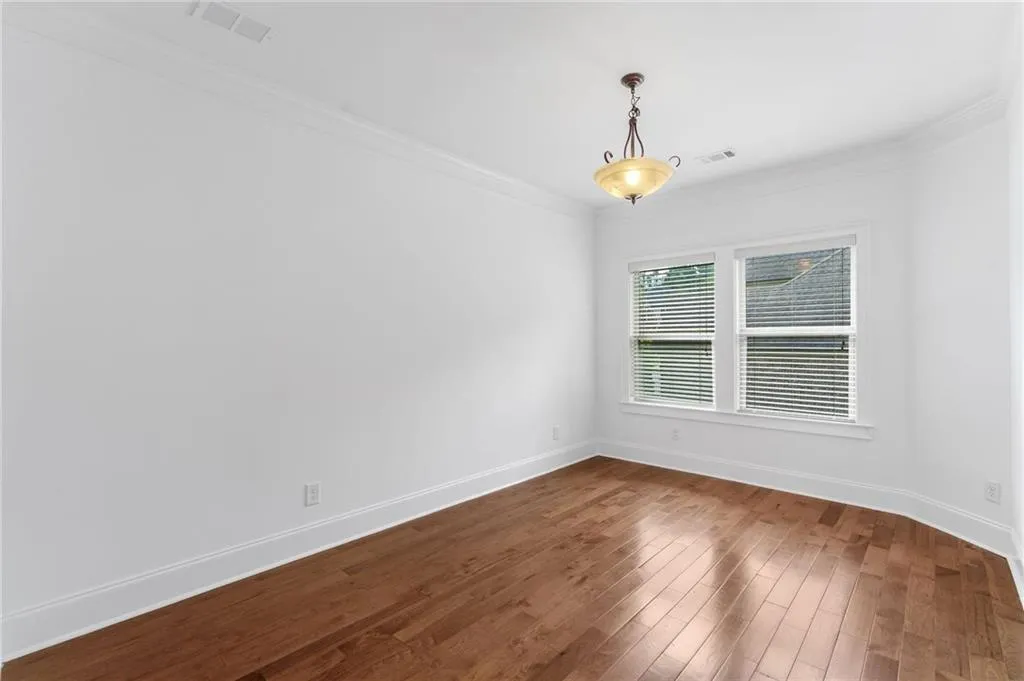 Primary office nook featuring hardwood / wood-style flooring and crown molding