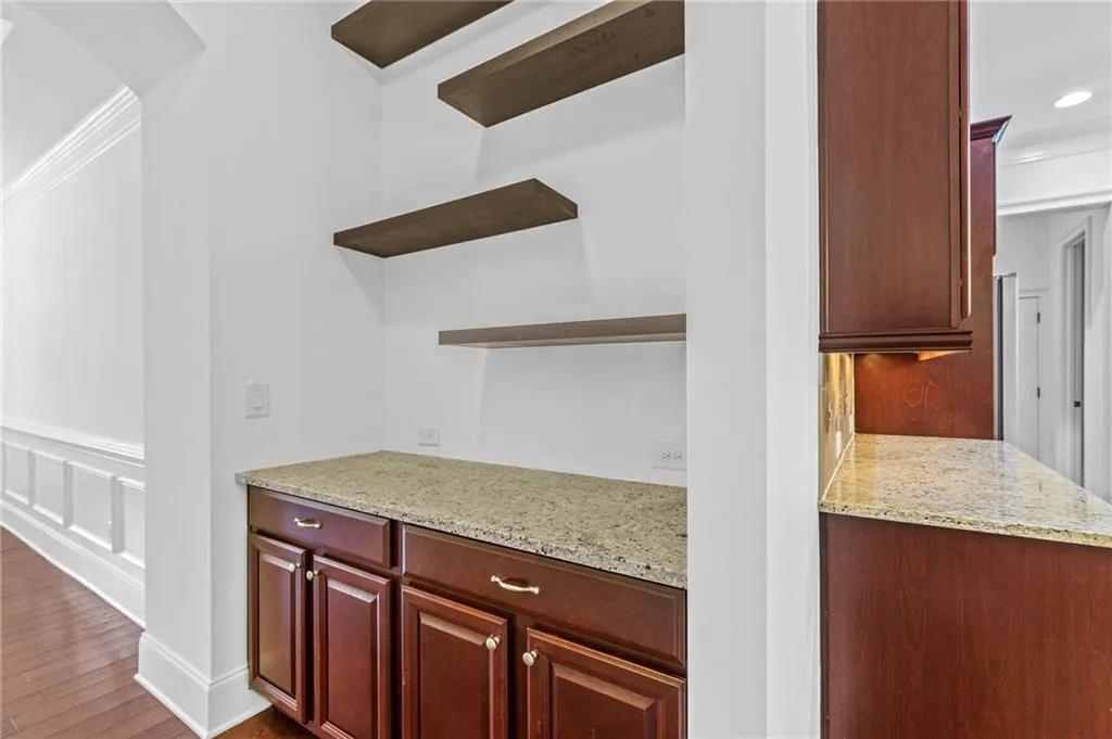 Kitchen with light stone countertops, crown molding, and dark hardwood / wood-style flooring