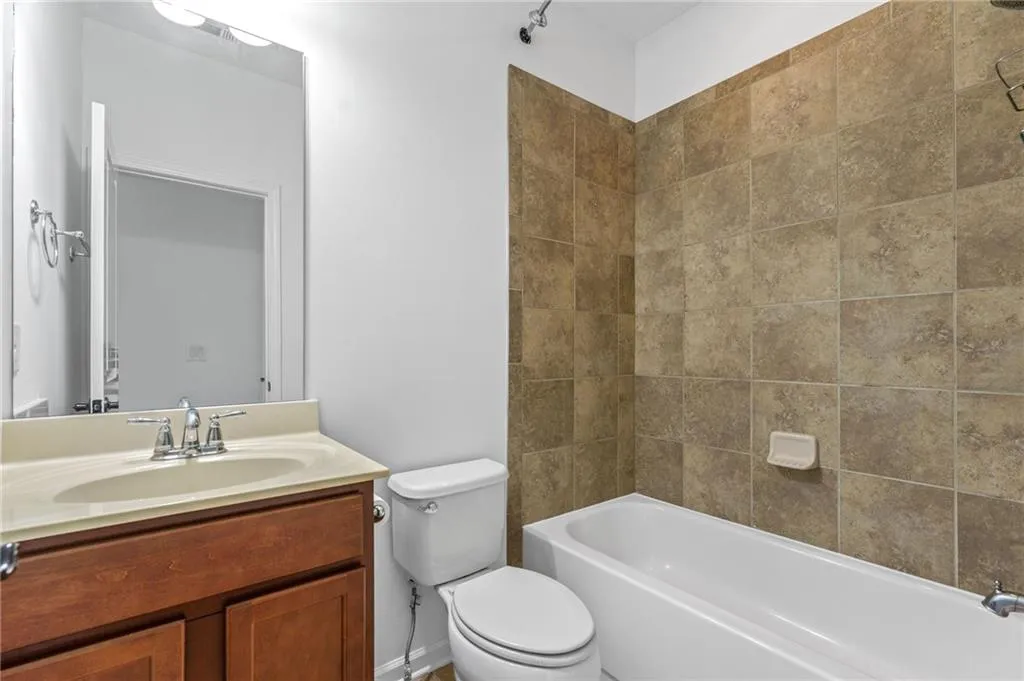 Full bathroom featuring tiled shower / bath, vanity, and toilet