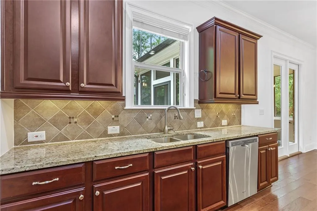 Kitchen with sink, decorative backsplash, hardwood / wood-style floors, ornamental molding, and stainless steel dishwasher