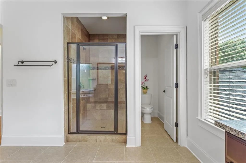 Primary Bathroom featuring a shower with door, toilet, and plenty of natural light