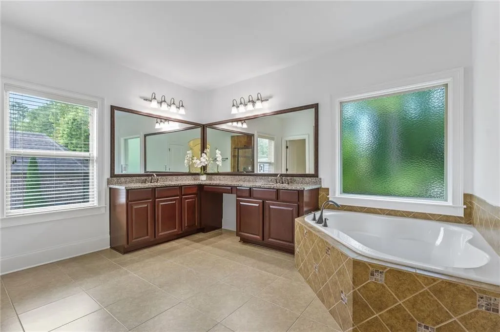 Primary Bathroom featuring vanity, tiled bath, plenty of natural light, and tile patterned flooring