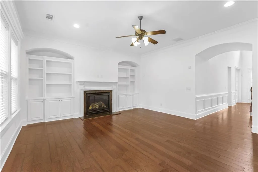 Living room with crown molding, a fireplace, dark hardwood / wood-style flooring, and ceiling fan