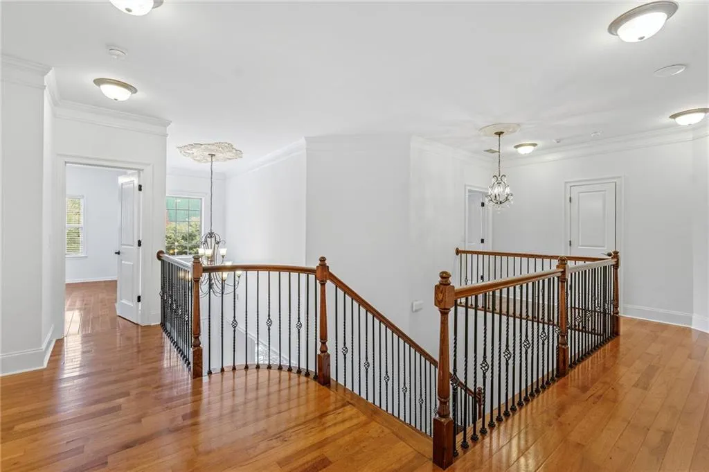 Upper level Corridor with an inviting chandelier, crown molding, and hardwood / wood-style floors