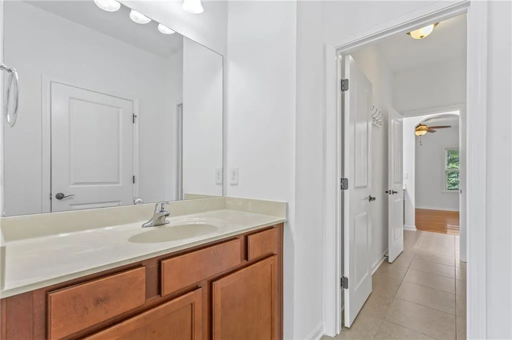 Jack and jill Bathroom with ceiling fan, vanity, and tile patterned floors