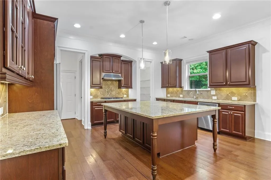 Kitchen featuring a breakfast bar, pendant lighting, a center island, stainless steel appliances, and dark hardwood / wood-style flooring