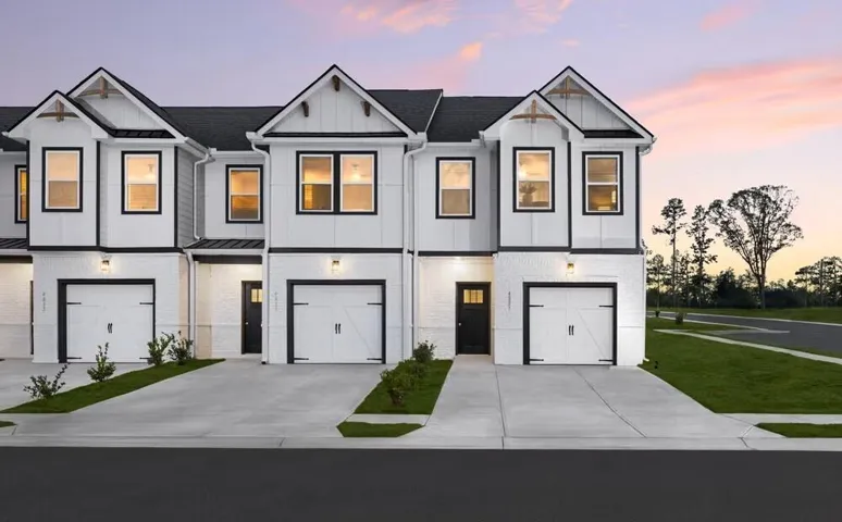 Contemporary townhome exteriors featuring white brick and vertical siding with contrasting dark trim