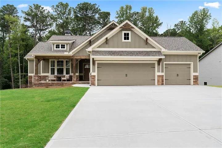 Craftsman house with a shingled roof, covered porch, driveway, a garage, and board and batten siding