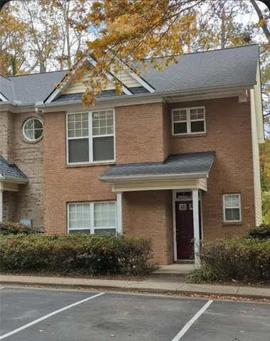 Traditional-style home featuring roof with shingles, uncovered parking, and brick siding